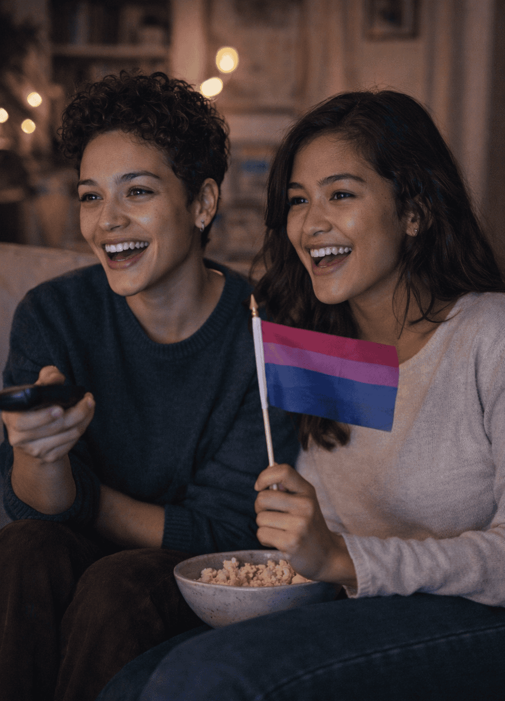 Two young adults watching TV together with a bisexual pride flag, representing positive bisexual representation in media